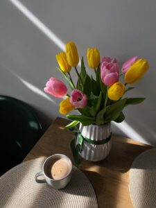 a vase of tulips and a cup of coffee on a table